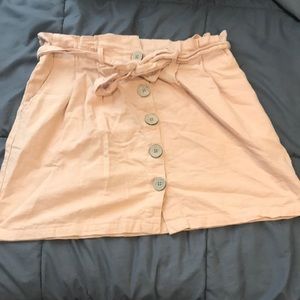 Light pink mid thigh length skirt with buttons down the center front.